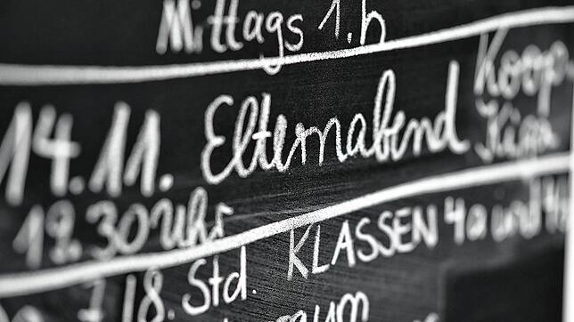 An einer Tafel werden den Schülern wichtige Termine mitgeteilt. Darunter findet sich auch der Elternabend.