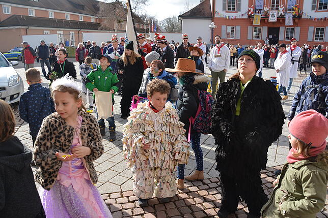 Die Kinder sammeln gierig die vom Rathausbalkon heruntergeworfenen Süßigkeiten auf.