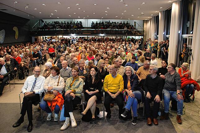 Das Publikum im voll besetzten Kursaal. Selbst an den Scheiben lehnen interessierte Zuhörer, die innen keinen Platz mehr gefunden haben.