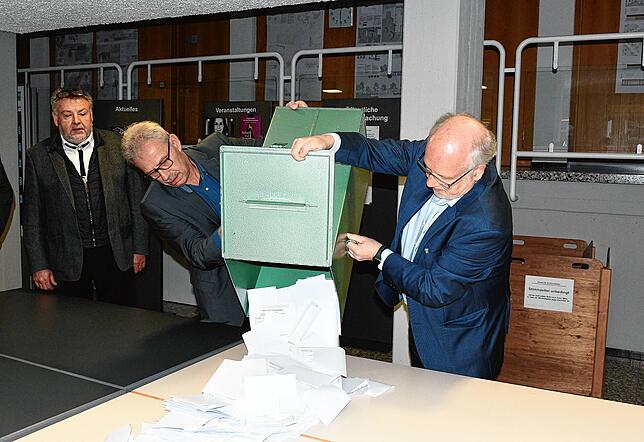 Michael Grambau (Mitte) und Wolfgang Weber (rechts) leeren die Urne mit den abgegebenen Stimmzetteln zur Bürgermeisterwahl 2023 in ...