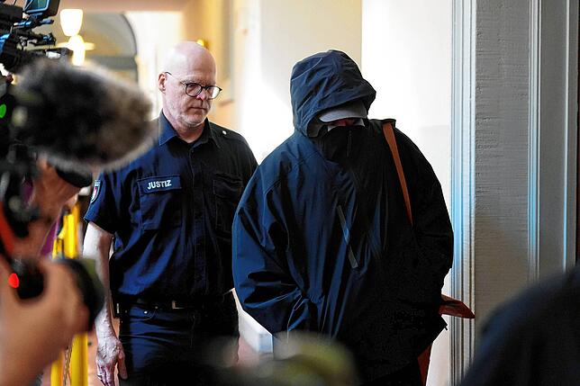 Ein Angeklagter wird von einem Polizisten zum Gerichtssaal geführt.