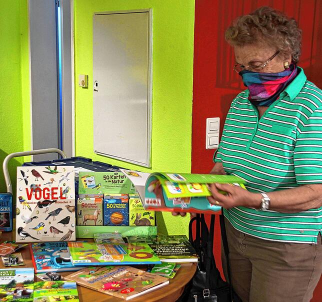 Charlotte Zoller blättert durch die Kinderbücher in der „Linzgau-Buchhandlung“. Davon halte sie das Maskentragen nicht ab, ...