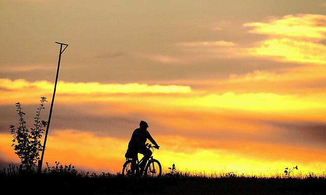Ein Radfahrer ist am Morgen kurz vor Sonnenaufgang unterwegs.