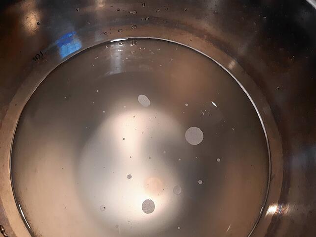 Wer genau hinsieht, sieht am Boden des Eimers die Hefe, die eben von der Flasche getrennt wurde.