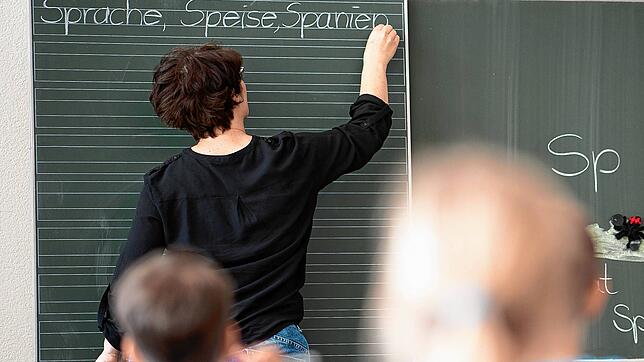 Eine Lehrerin schreibt etwas an die Tafel. Soll sie finanziell belohnt werden, wenn sie ihre Arbeit besonders gut macht?