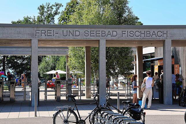 Menschen stehen vor dem Frei- und Seebad Fischbach an der Kasse an.