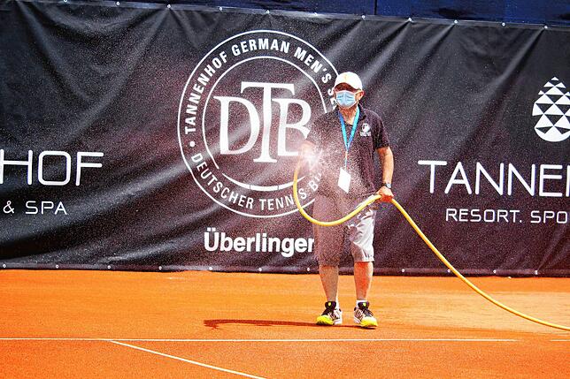 Platzwart Otto Jakob beim Bewässern des Tenniscourt – natürlich unter Einhaltung der Corona-Hygieneverordnung, mit Mund-Nasen-Maske.