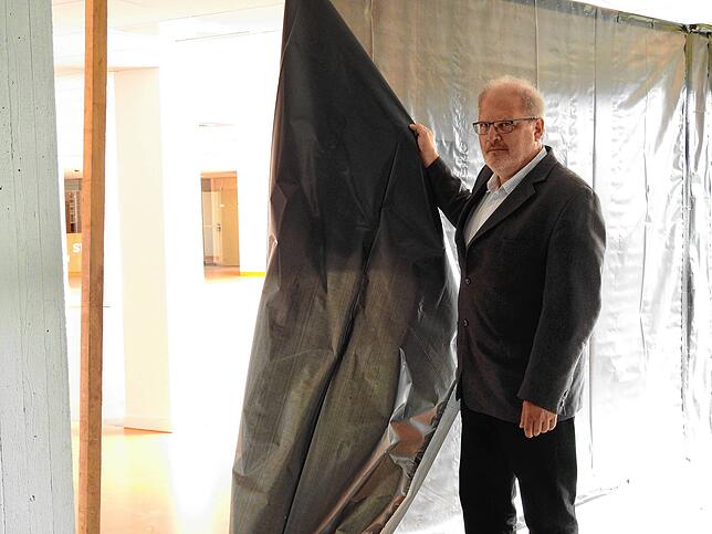 Campusmanager Peter Mast zieht im September 2019 einen Staubschutzvorhang zu einer Abteilung auf, in der Abbrucharbeiten laufen.