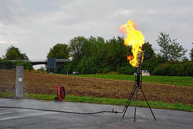 Die Flamme hebt sich gut sichtbar vom dunkelgrauen Himmel ab.