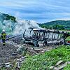 Die Feuerwehr löscht den Brand in dem Bus, der in der Nähe von Ulm mit einem Zug kollidierte.
