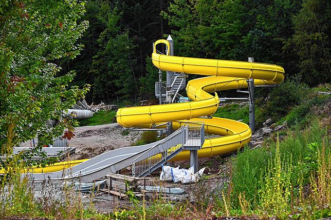 Die neue Halbschalenrutsche windet sich mit 73,5 Meter Länge dem Landebecken entgegen. Im Vordergrund ist die Dreifachrutsche zu sehen.