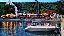 Blick vom Bootsanleger auf das Rebgut Haltnau. Der zugehörige Biergarten ist im Vordergrund zu erkennen, bunte Lichterketten sorgen für ...