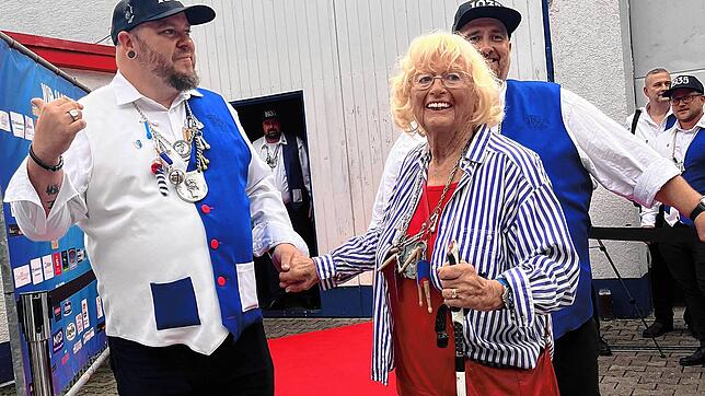 Jörg Uhrig, Tambour des Trommlerzugs, nimmt Trommlermotter Helga Duffner auf dem roten Teppich an die Hand. Mit dabei zweiter Tambour ...