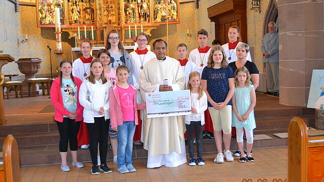 Father Joe mit dem von den Sternsingern überreichten Scheck und Gruppenleiterin Sabrina Burczyk (rechts außen).
