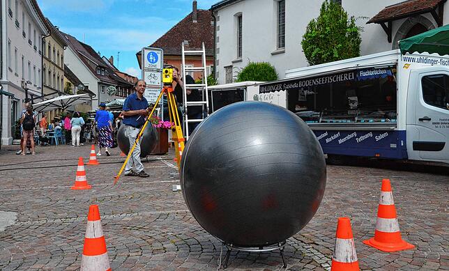 David Fuchs und ein Mitarbeiter vom Deggenhauser Metallatelier vermessen im Juli 2024 den Standort der Brunnenkugeln.