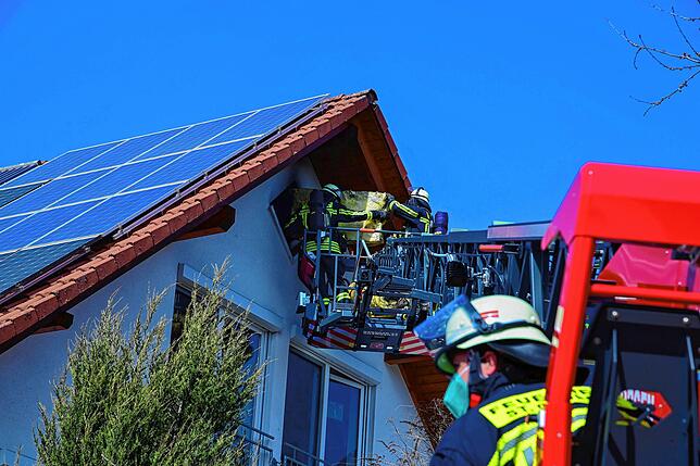 Feuerwehrleute bringen das brennende Dämmmaterial aus dem Dachgeschoss.
