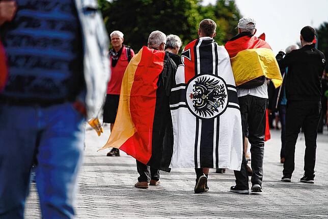 Demonstranten mit deutschen Fahnen, auch der Reichsflagge, über den Schultern.