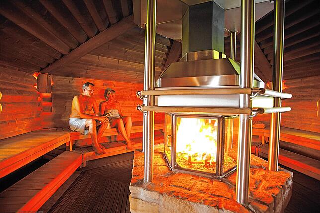 Im Zentrum der Feuersauna befindet sich ein verglaster Kamin. Bei 110 Grad lässt es dich dort gut schwitzen.