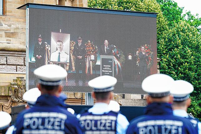 Die Trauerfeier für Rouven Laur wird auf einer Leinwand übertragen.