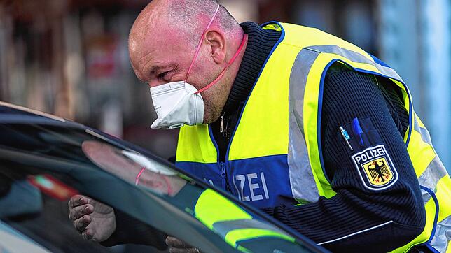 Ein Bundespolizist mit Schutzmaske kontrolliert am Grenzübergang Weil am Rhein an der Einreise aus der Schweiz nach Deutschland einen ...