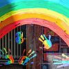 Kinderhände und ein Regenbogen sind an einer Kita zu sehen.