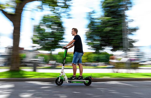 Ein Mann fährt in Stuttgart auf einem E-Tretroller des Anbieters Lime, einem von drei Leihanbietern.