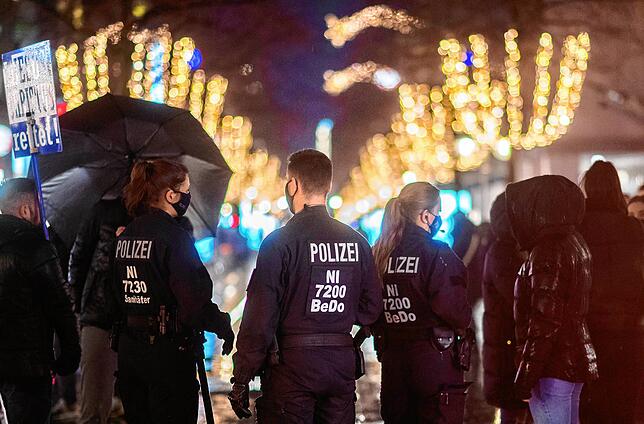 Polizisten stehen am in einer Innenstadt und kontrollieren die Einhaltung der Corona-Verordnung.