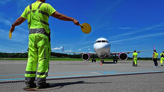 Ein Mitarbeiter des Bodensee-Airports weist ein Passagierflugzeug zu seinem Platz. (Archivbild)
