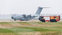 Ein Airbus-Militärtransporter A400M fährt an einem Einsatzfahrzeug der Flughafenfeuerwehr vorüber.
