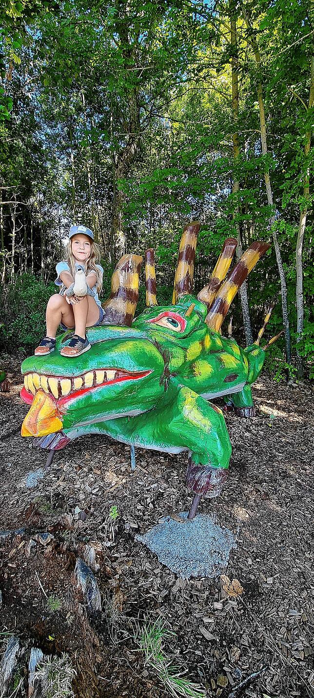 Die achtjährige Merle erkundet einen hölzernen Drachen am Eingang des Schlühuwanaparks.