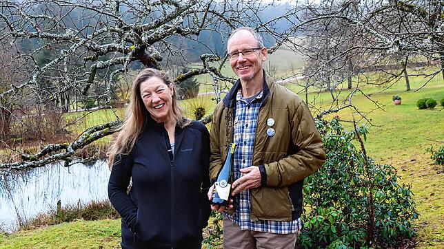Wendy LeBlanc und Patrick Mann mit einer Flasche ihres Ciders vor Streuobstbäumen im Unterkirnacher Moosloch. Bild: Cornelia Putschbach