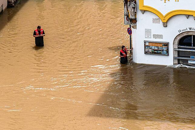 Rettungskräfte stehen im Hochwasser der Donau.