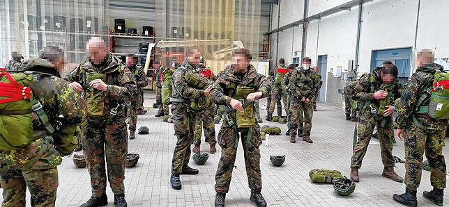 In Zweierteams legen die Soldatinnen und Soldaten den Fallschirm an.