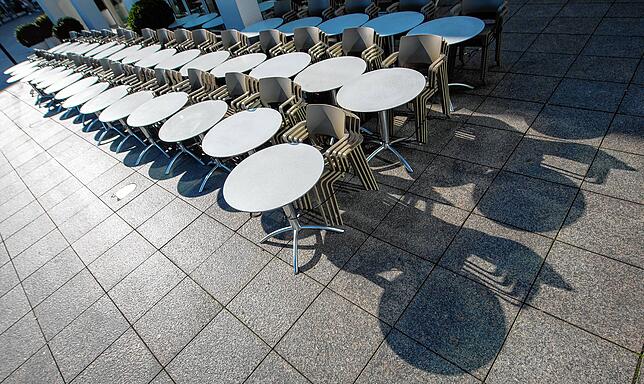 Rückblick zum Frühjahr: Tische und Stühle eines Straßencafes sind in der Sonne aufgereiht, weil Gastronomiebetriebe wegen Corona nicht ...