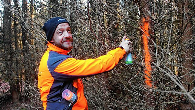 Forstwirt Jens Brauer markiert mit Farbe die Trasse für den Vollernter.
