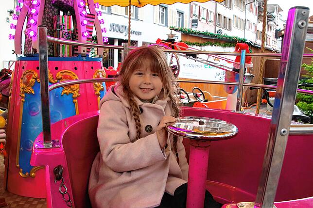Anziehungspunkt für Kinder ist das Kinderkarussell. Auch Aliya dreht als erstes ihre Runden. Die Fahrt kostet 2,50 Euro statt 3 Euro.