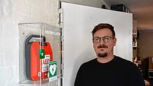 Marius Riether, betrieblicher Ersthelfer, neben dem neuen AED-Gerät im „atelier 522“.