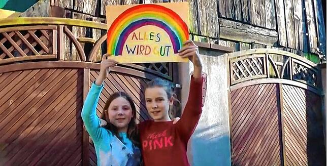 Linn und Fiona Trefzger zeigen ein Plakat im Video. Sie singen die Originalversion des Liedes „Die Welt steht still.“
