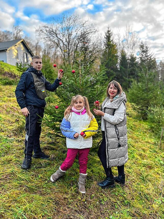 Die Ukrainerin Svitlana Kutsenko steht mit ihren Kindern vor einem Weihnachtsbaum. Das große Familienfest wird nur klein gefeiert.