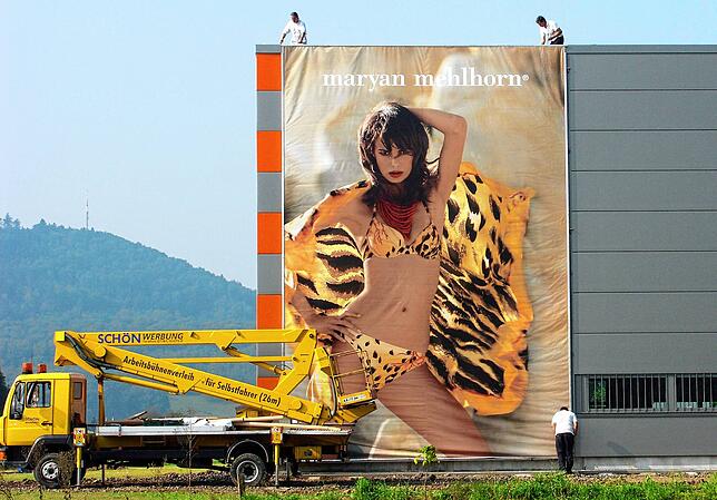 Bikinischönheiten auf riesigen Plakaten an der Fassade des neuen Logistikzentrums in Luttingen.