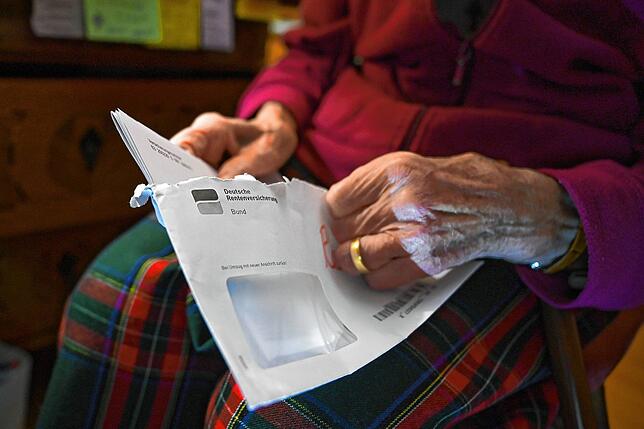 Eine Seniorin hält ihren Rentenbescheid in der Hand. Gerade Frauen sind im Alter oft nicht gut abgesichert.