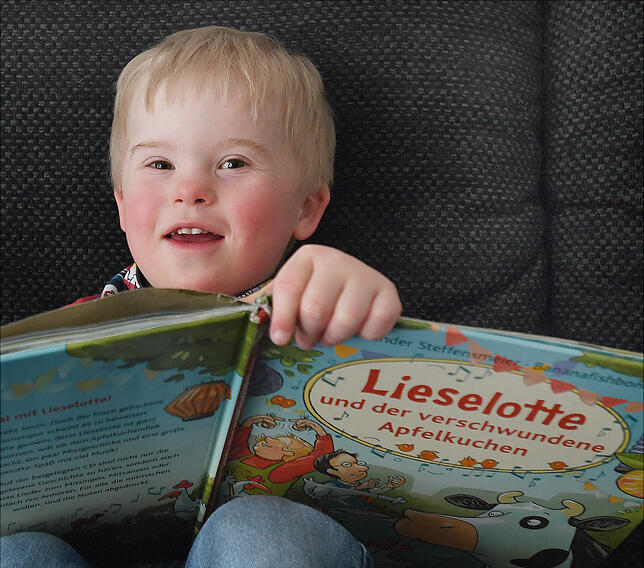 Der dreijährige Luis sieht sich eines seiner Bilderbücher an. Luis kam mit dem Downsyndrom zur Welt.