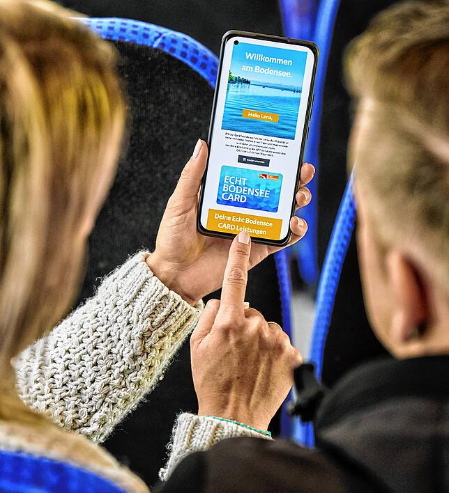 Urlauber fahren mit der EBC-Gästekarte, digital hinterlegt auf dem Smartphone, Bus.