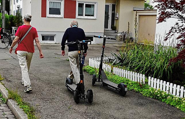 Sieht so aus, als hätten diese beiden Fußgänger die Roller hier einfach abgestellt. Haben sie aber nicht, sie marschieren nur stoisch ...
