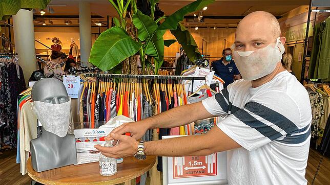 Dominic Schmieder desinfiziert seine Hände, bevor er das Textilfachgeschäft in der Waldshuter Straße in Jestetten betritt. Masken gibt ...