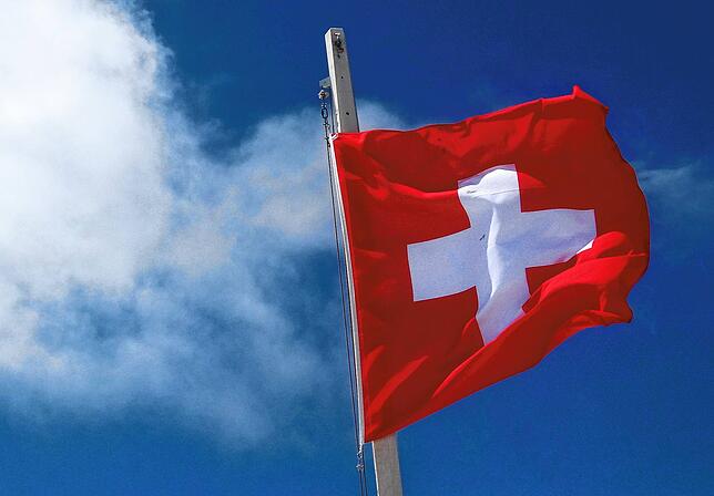 Eine Schweizerflagge weht im Wind unter dem eidgenössischen Himmel.