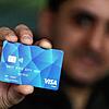 Ein Geflüchteter hält eine Debitcard in der Hand (Symbolbild). Ab Januar sollen Asylbewerber in mehreren Pilotlandkreisen im Land mit ...