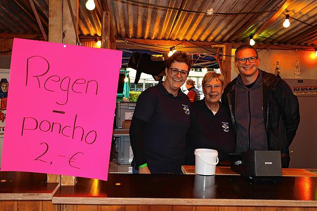 Am Stand des Musikvereins Neufrach sind Regenponchos neben Burgern und Pommes der Renner. Regina Fleischmann, Petra und Markus Meier ...