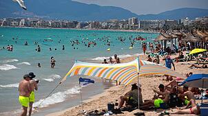 Menschen sonnen sich, genießen das Wetter und schwimmen am Strand von Arenal auf Mallorca. Doch plötzlich wird eine ältere Urlauberin ...
