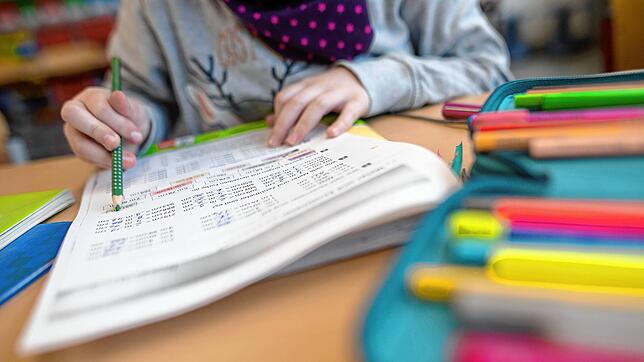 (Symbolbild) Ein Mädchen löst in einer Grundschule eine Matheaufgabe. Könnten kommunale Einrichtungen in Konstanz vom Privatangebot ...